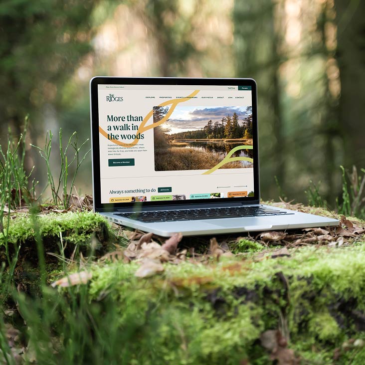 The Ridges Sanctuary website loaded onto a laptop sitting on the forest floor.